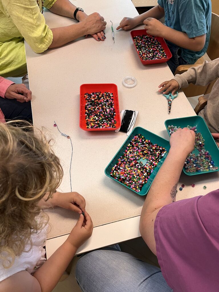 Kinder basteln mit Perlen an einem Tisch