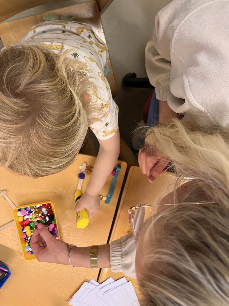 Kinder basteln mit Perlen an einem Tisch