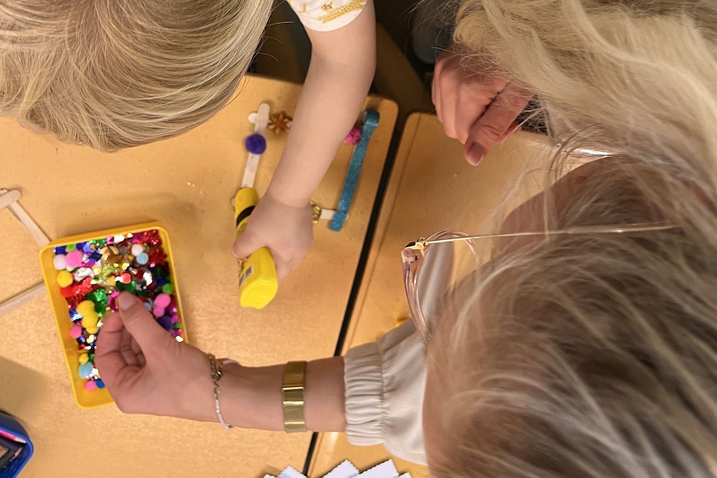 Kinder basteln mit Perlen an einem Tisch