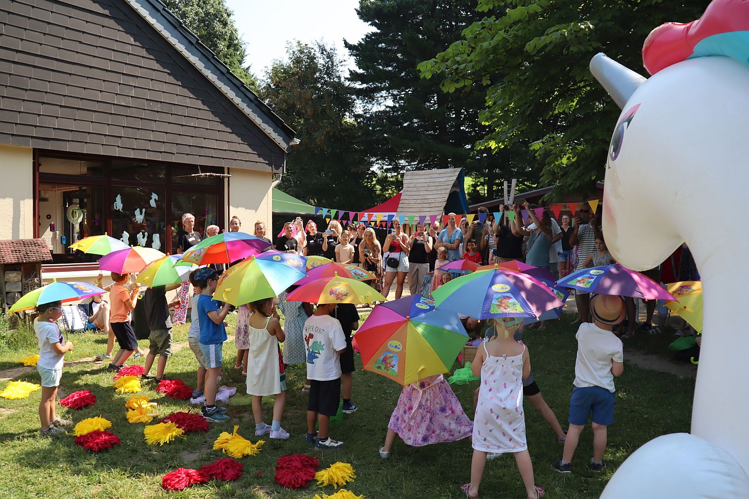 Kinder tanzen und schwingen bunte Regenschirme