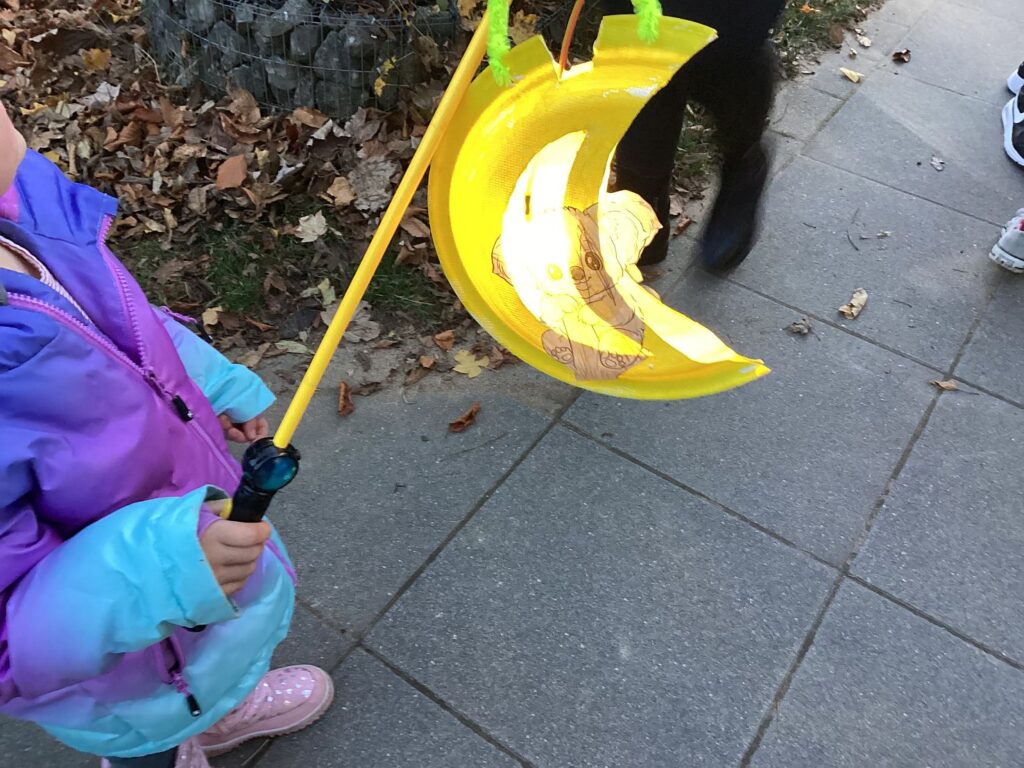 Ein Kind trägt eine Laterne in Mondform