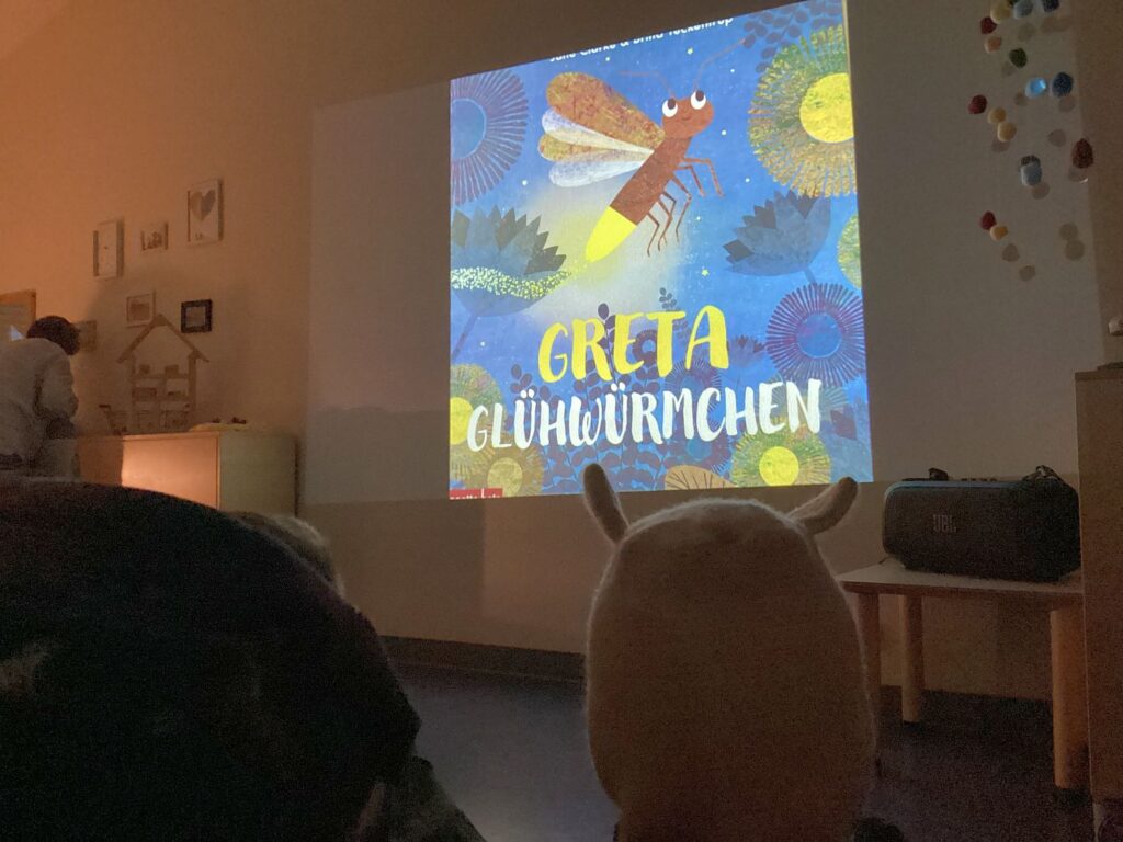 An der Wand wird das BIld aus dem Buch "Greta Glühwürmchen" gezeigt 