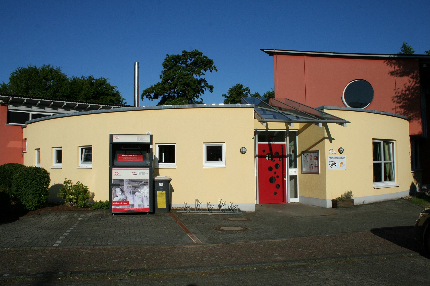 Das Familienzentrum von außen, ein rundes Gebäude, gelb gestrichen, rote Tür