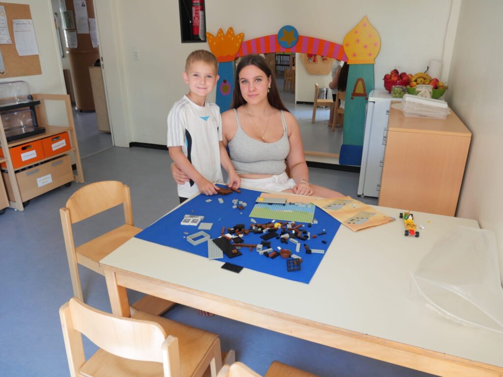 Mutter und Sohn sitzen an einem Tisch mit bunten Bausteinen