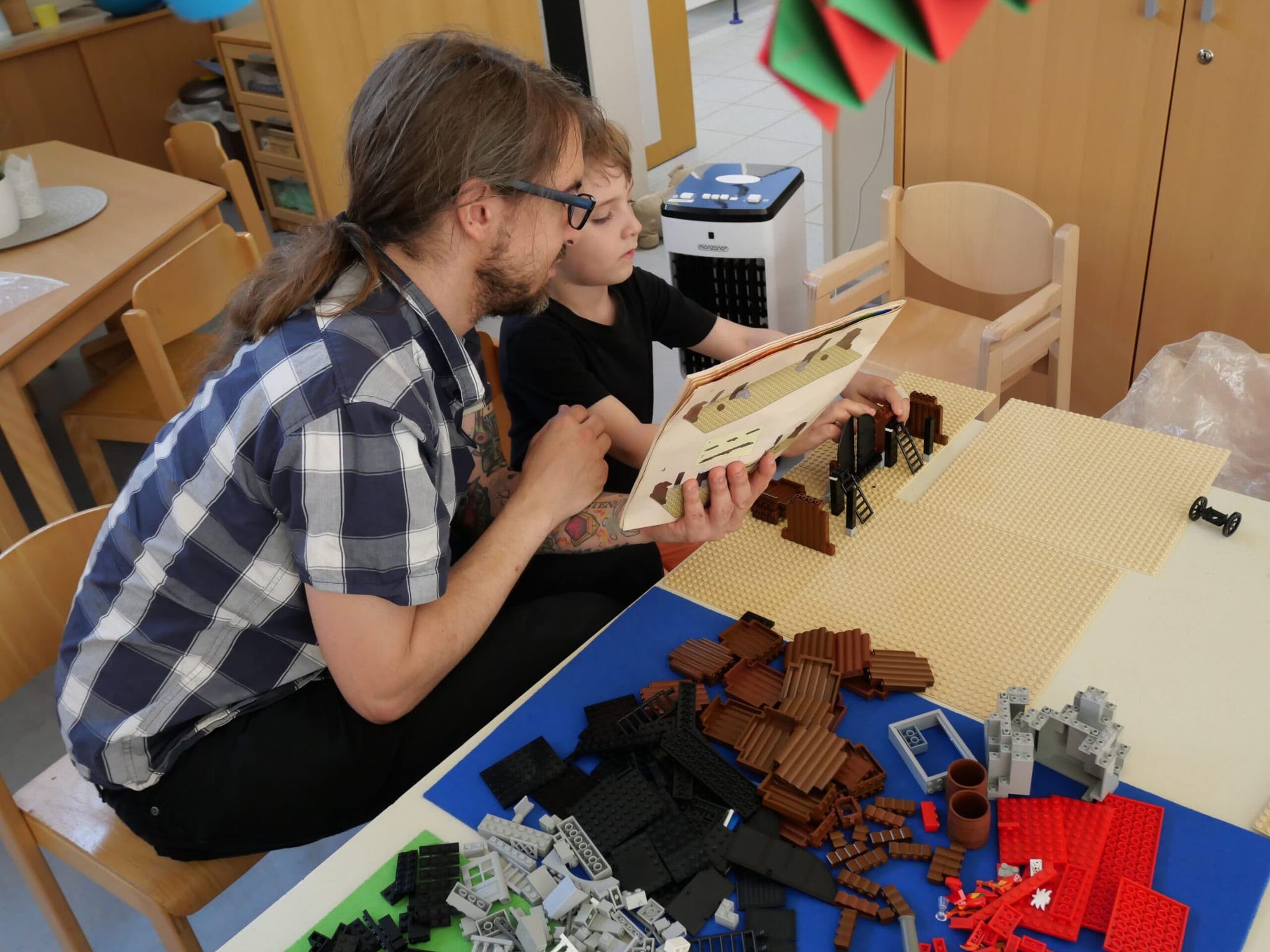 Brick_Solution 2026_Kita Strobel (12) Ein Vater und sein Sohn bauen an einem Tisch mit Legosteinen