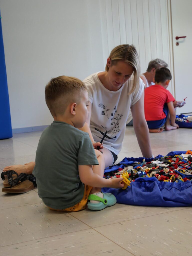 Mutter und Sohn bauen auf dem Boden sitzend
