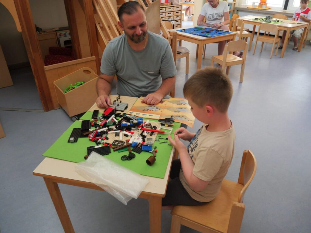 Vater und Sohn sitzen am Tisch und bauen mit bunten Steinchen