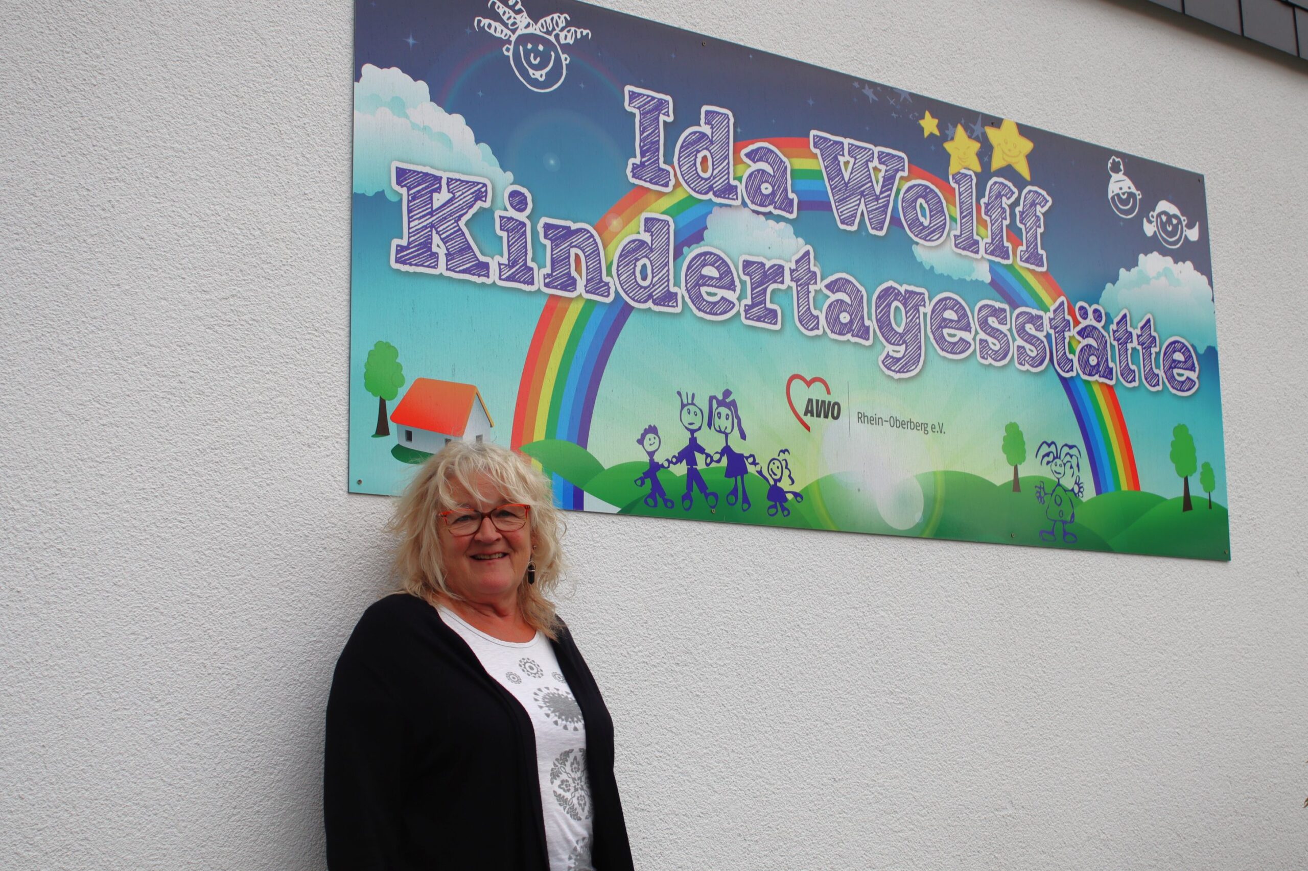 KiTa-Leitung vor dem Schild der Einrichtung