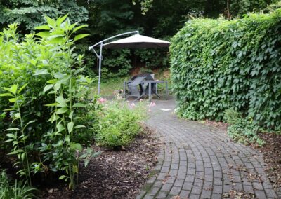 Gemeinschaftsgarten mit Sonnenschirm und vielen großen Pflanzen