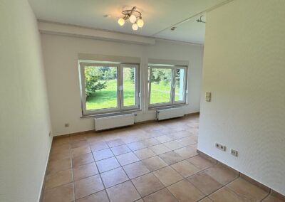 ein Zimmer mit zwei großen Fenstern, weiße Wände