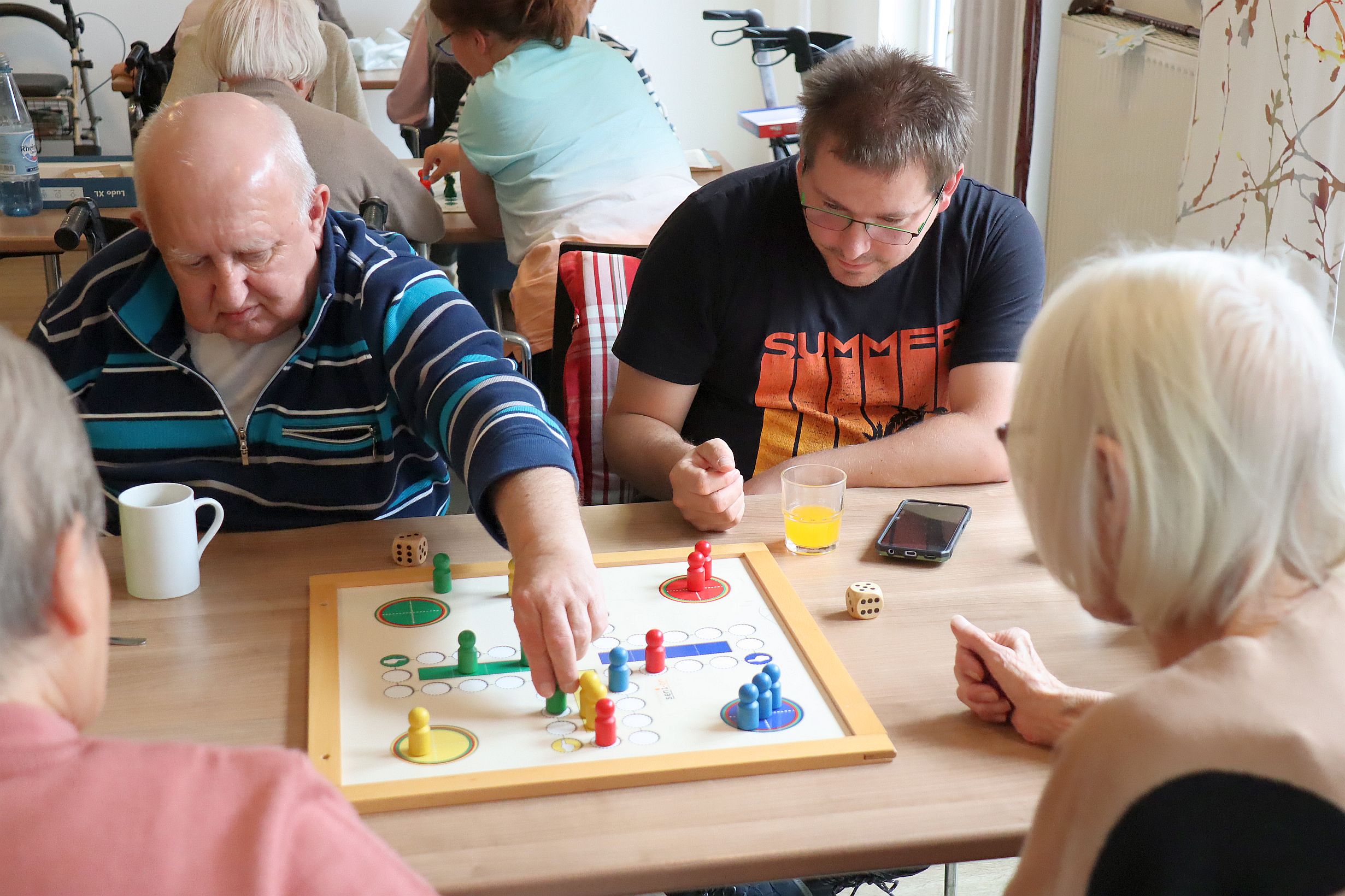 AWO_BWO Spiele 2025_8 Ein jüngerer Mann und ein älterer Herr spielen Mensch-ärgere-Dich-nicht mit großen Spielfiguren