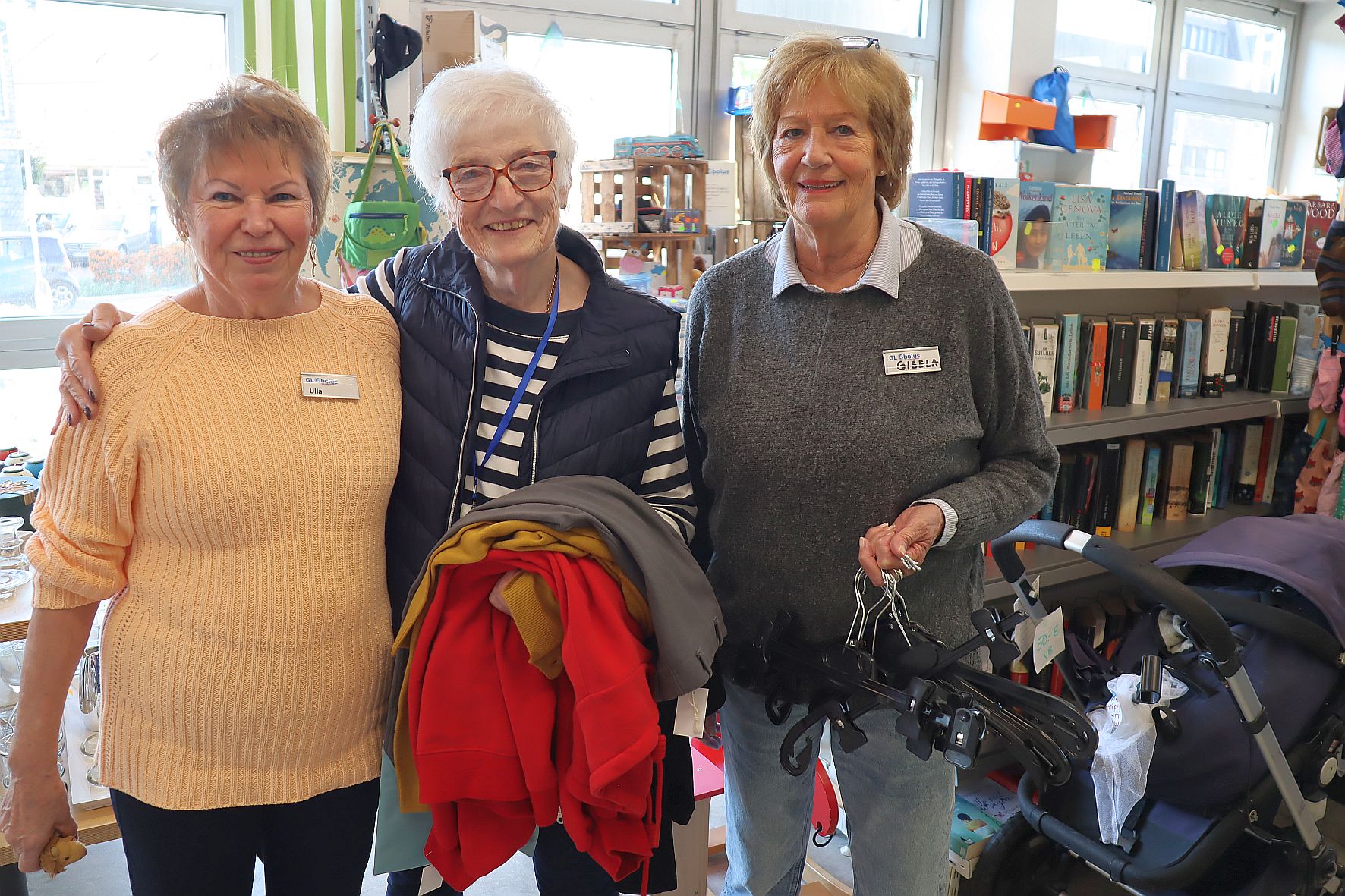 Drei ehrenamtlich mitarbeitende Damen stehen vor den Kleiderständern mit der Secondhand-Ware