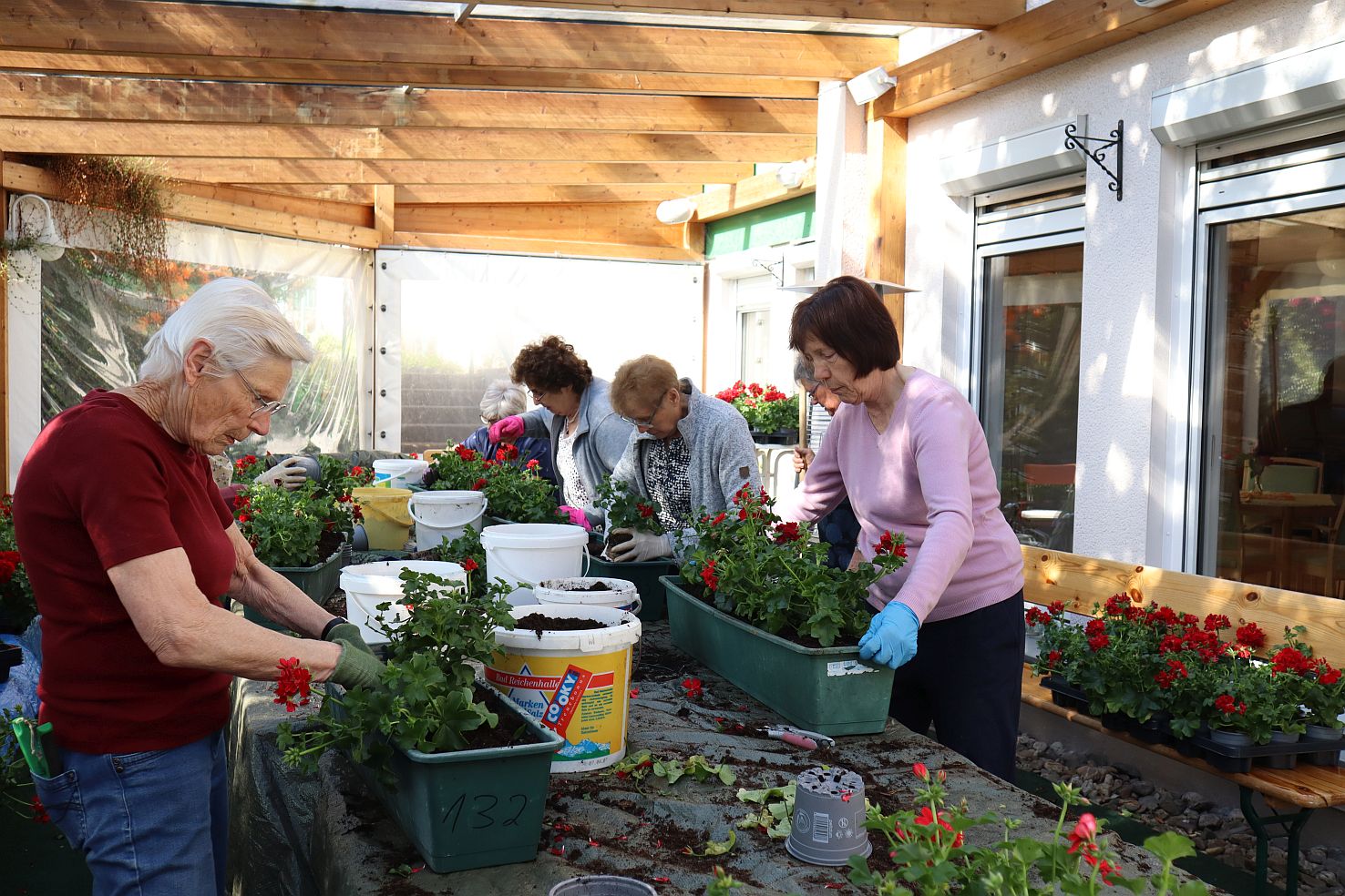 Frauen bepflanzen an einem Tisch die Blumenkästen
